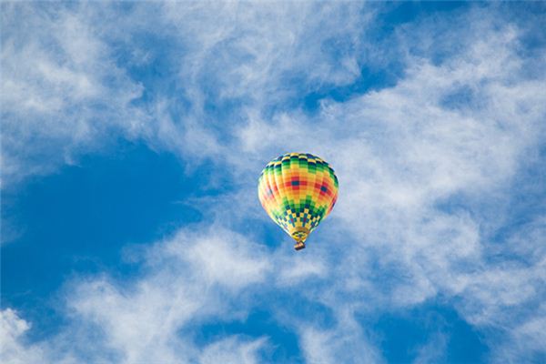 What is the meaning and symbolism of sitting in a hot air balloon in a dream?